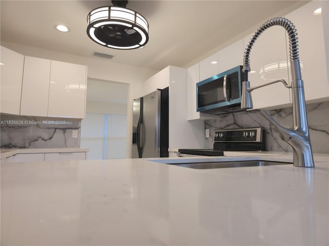 7771 NW 46th St, Lauderhill, FL 33351 - kitchen with stainless steel appliances, white cabinets, modern cabinets, light countertops, and tasteful backsplash