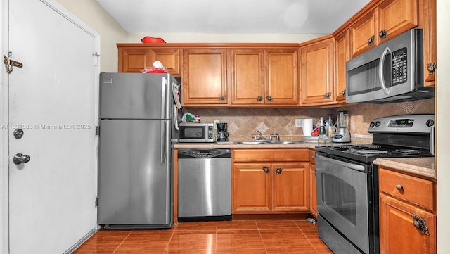 4821 NW 22nd Ct Unit 110, Lauderhill, FL 33313 - kitchen featuring stainless steel appliances, brown cabinetry, tasteful backsplash, and light countertops