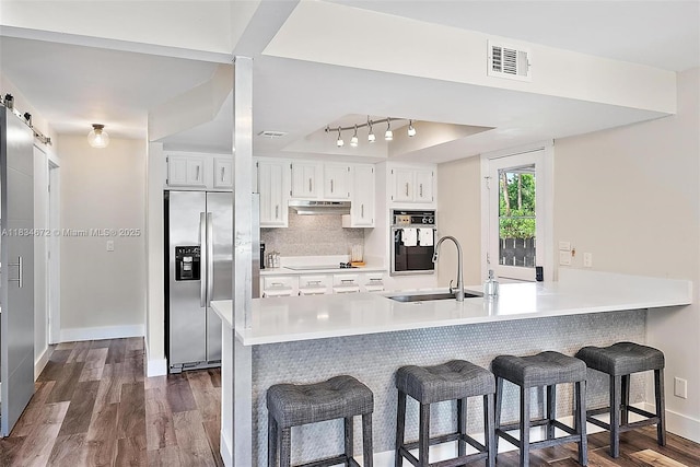 7264 159th Ct N, Palm Beach Gardens, FL 33418 - kitchen with black appliances, under cabinet range hood, a breakfast bar, a peninsula, and light countertops