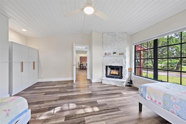 7264 159th Ct N, Palm Beach Gardens, FL 33418 - bedroom featuring vaulted ceiling, wooden ceiling, a stone fireplace, wood finished floors, and a ceiling fan