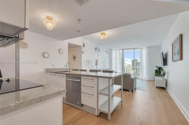 185 SW 7th St Unit 2204, Miami, FL 33130 - kitchen with stainless steel dishwasher, light wood-style floors, white cabinets, black electric cooktop, and a peninsula
