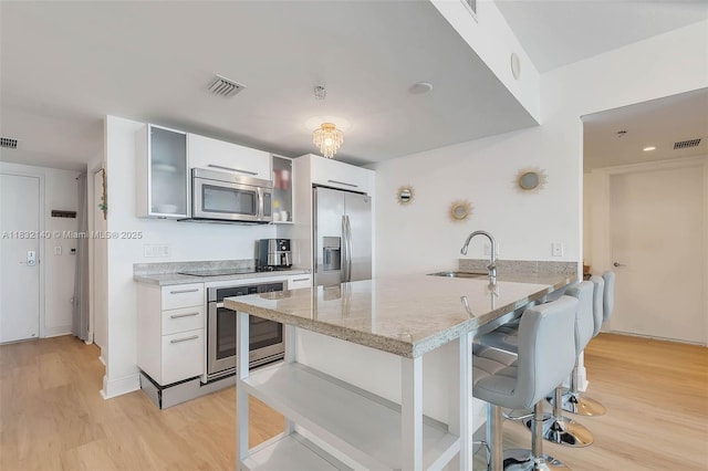 185 SW 7th St Unit 2204, Miami, FL 33130 - kitchen featuring stainless steel appliances, a breakfast bar, light wood-style flooring, and a peninsula