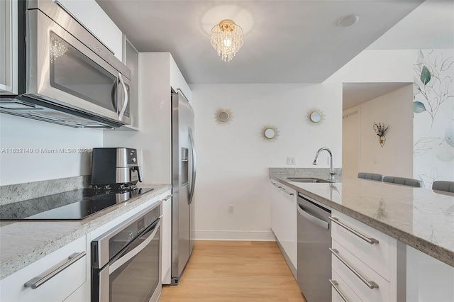 185 SW 7th St Unit 2204, Miami, FL 33130 - kitchen featuring stainless steel appliances, light stone countertops, light wood-style flooring, and white cabinetry