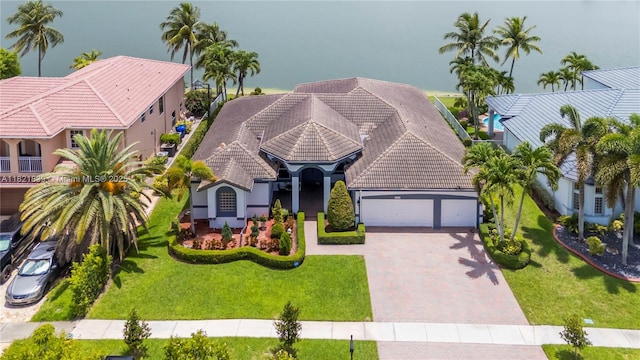 18633 SW 24th St, Miramar, FL 33029 - view of front of house with an attached garage, decorative driveway, a tiled roof, stucco siding, and a front lawn