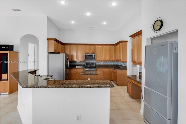 18633 SW 24th St, Miramar, FL 33029 - kitchen with stainless steel appliances, light tile patterned flooring, arched walkways, dark stone countertops, and recessed lighting