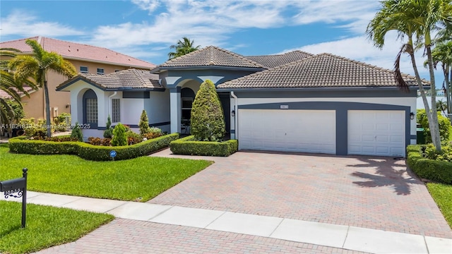 18633 SW 24th St, Miramar, FL 33029 - mediterranean / spanish home featuring decorative driveway, a garage, stucco siding, a front lawn, and a tiled roof