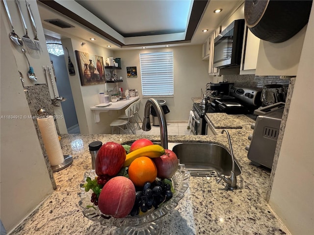 3910 Inverrary Blvd Unit 603-B, Lauderhill, FL 33319 - kitchen featuring stainless steel appliances, light stone counters, a tray ceiling, and tasteful backsplash