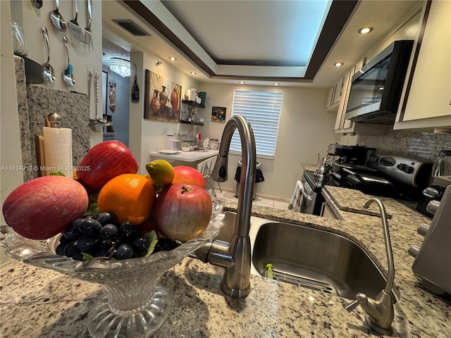 3910 Inverrary Blvd Unit 603-B, Lauderhill, FL 33319 - kitchen featuring appliances with stainless steel finishes, backsplash, a tray ceiling, light stone countertops, and recessed lighting