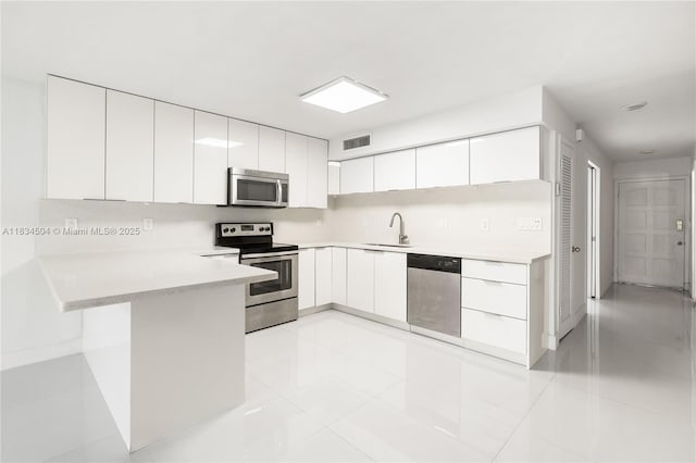 20218 NE 34th Ct Unit 52, Aventura, FL 33180 - kitchen featuring appliances with stainless steel finishes, a peninsula, light countertops, white cabinetry, and modern cabinets