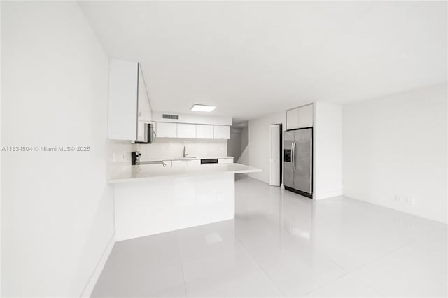 20218 NE 34th Ct Unit 52, Aventura, FL 33180 - kitchen featuring stainless steel refrigerator with ice dispenser, light countertops, white cabinets, a peninsula, and light tile patterned flooring