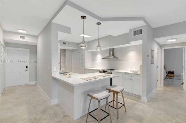 3205 NE 184th St Unit 9106, Aventura, FL 33160 - kitchen with wall chimney range hood, a breakfast bar area, white cabinetry, light countertops, and a peninsula