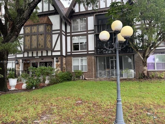 3690 Inverrary Dr Unit 1T, Lauderhill, FL 33319 - back of house featuring a yard, brick siding, and stucco siding