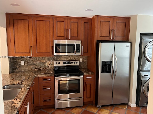 3016 NE 21st Ter Unit 3016, Fort Lauderdale, FL 33306 - kitchen featuring stainless steel appliances, stacked washer / drying machine, tasteful backsplash, and dark stone counters
