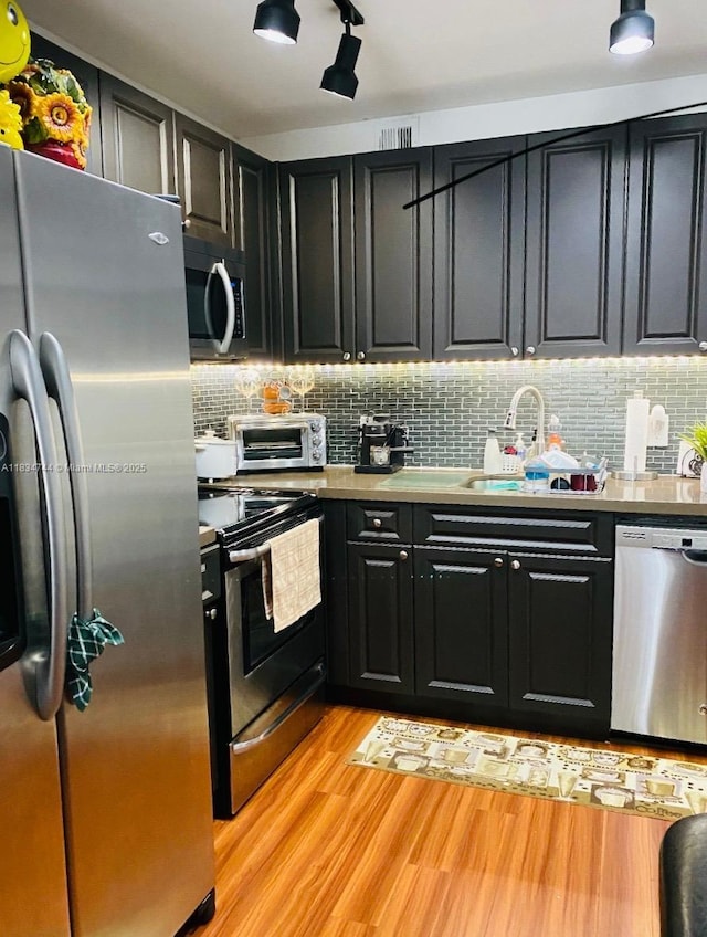 13255 SW 7th Ct Unit 213D, Pembroke Pines, FL 33027 - kitchen with appliances with stainless steel finishes, light wood-style floors, dark cabinets, and decorative backsplash