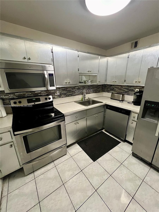 1470 NE 125th Ter Unit 814, North Miami, FL 33161 - kitchen featuring appliances with stainless steel finishes, decorative backsplash, light countertops, and light tile patterned flooring