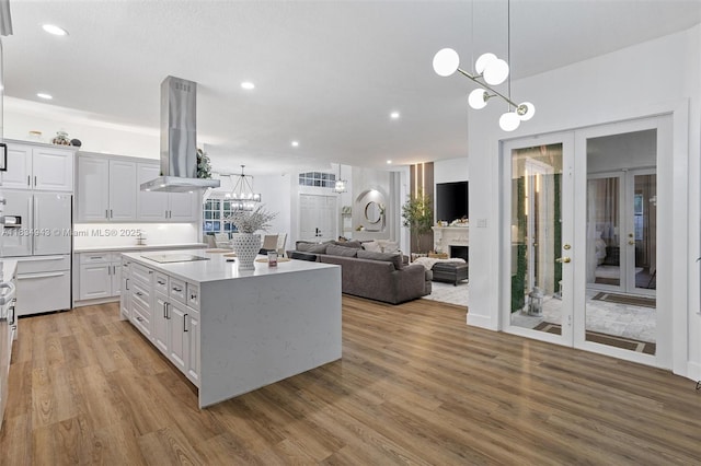 14501 SW 33rd Ct, Miramar, FL 33027 - kitchen featuring white fridge with ice dispenser, island exhaust hood, a chandelier, light wood-style floors, and white cabinets