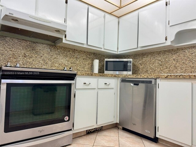 201 180th Dr Unit 114, Sunny Isles Beach, FL 33160 - kitchen with appliances with stainless steel finishes, ventilation hood, light tile patterned flooring, white cabinets, and light stone counters