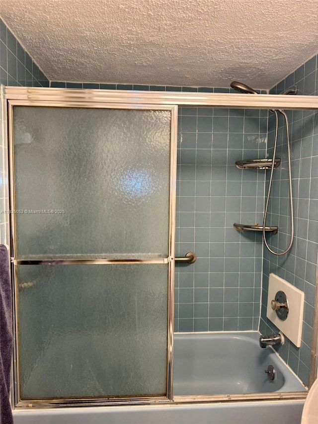 201 180th Dr Unit 114, Sunny Isles Beach, FL 33160 - bathroom with a textured ceiling and bath / shower combo with glass door