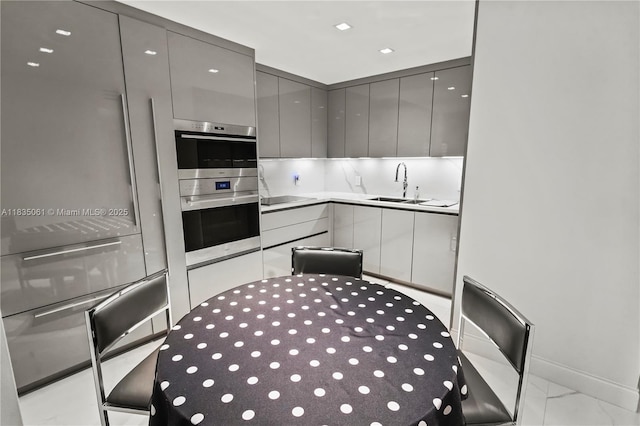 8877 Collins Ave Unit 705, Surfside, FL 33154 - kitchen with gray cabinets, double oven, modern cabinets, light marble finish floors, and black electric cooktop