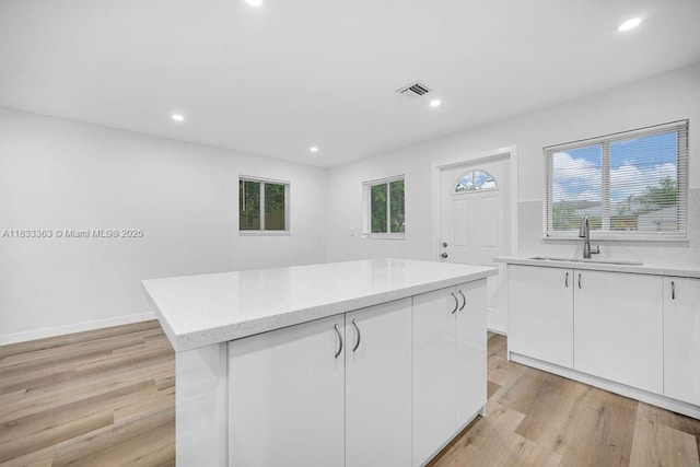 5201 Wiley St, Hollywood, FL 33021 - kitchen with white cabinets, recessed lighting, light wood-type flooring, a kitchen island, and light stone counters