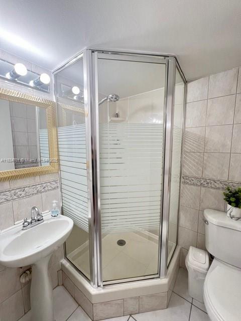 250 181st Dr Unit 212, Sunny Isles Beach, FL 33160 - bathroom featuring tile walls, tile patterned floors, a stall shower, and tasteful backsplash