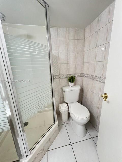 250 181st Dr Unit 212, Sunny Isles Beach, FL 33160 - bathroom with tile walls, a stall shower, and tile patterned flooring