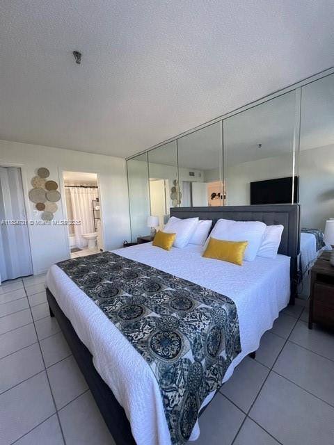 250 181st Dr Unit 212, Sunny Isles Beach, FL 33160 - bedroom featuring tile patterned flooring, a textured ceiling, and ensuite bath
