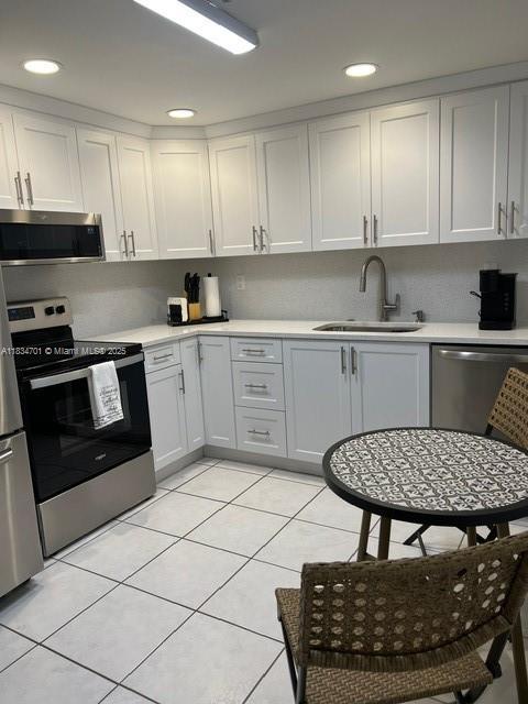 250 181st Dr Unit 212, Sunny Isles Beach, FL 33160 - kitchen with appliances with stainless steel finishes, light countertops, light tile patterned floors, white cabinets, and recessed lighting