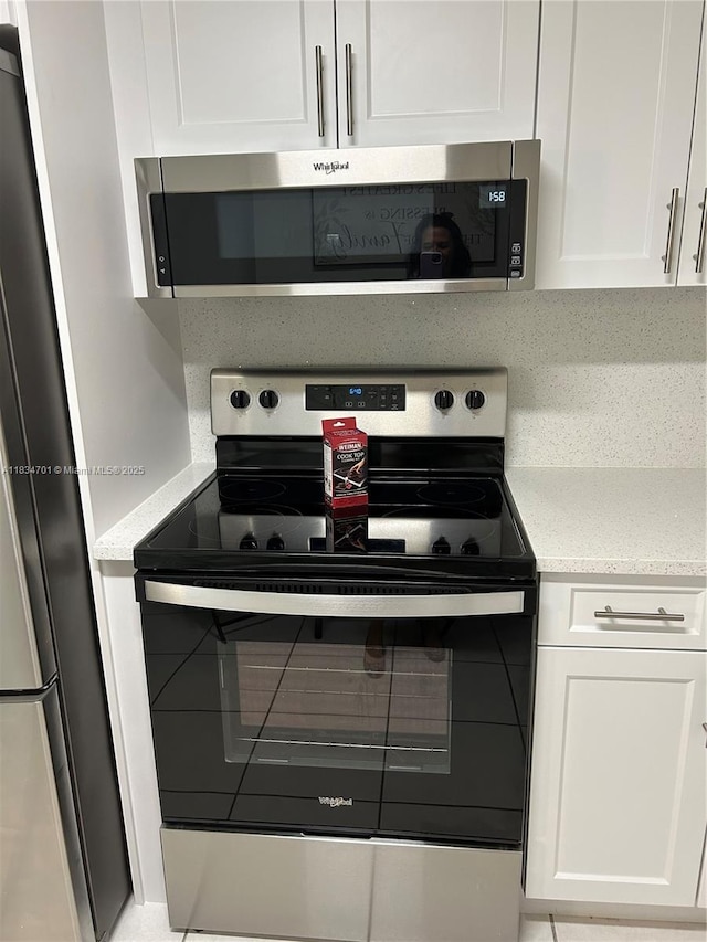 250 181st Dr Unit 212, Sunny Isles Beach, FL 33160 - kitchen featuring appliances with stainless steel finishes, white cabinetry, and light stone counters
