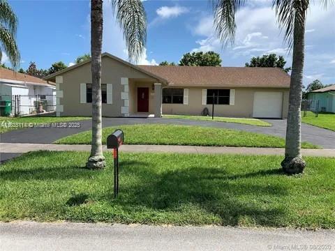 12600 SW 10th Ct, Davie, FL 33325 - ranch-style house with curved driveway, an attached garage, stucco siding, and a front lawn