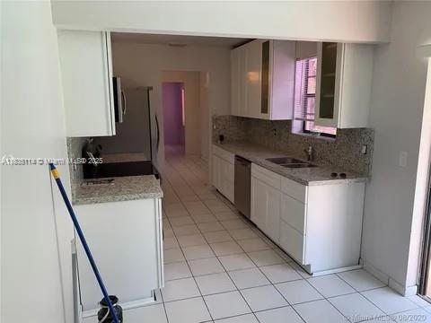 12600 SW 10th Ct, Davie, FL 33325 - kitchen with stainless steel dishwasher, backsplash, white cabinetry, light tile patterned floors, and light countertops