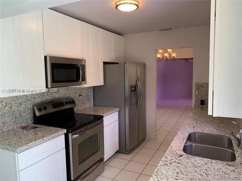 12600 SW 10th Ct, Davie, FL 33325 - kitchen with stainless steel appliances, light tile patterned flooring, a chandelier, and white cabinetry