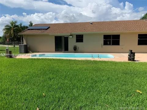 12600 SW 10th Ct, Davie, FL 33325 - rear view of house featuring solar panels, stucco siding, a yard, and a patio area