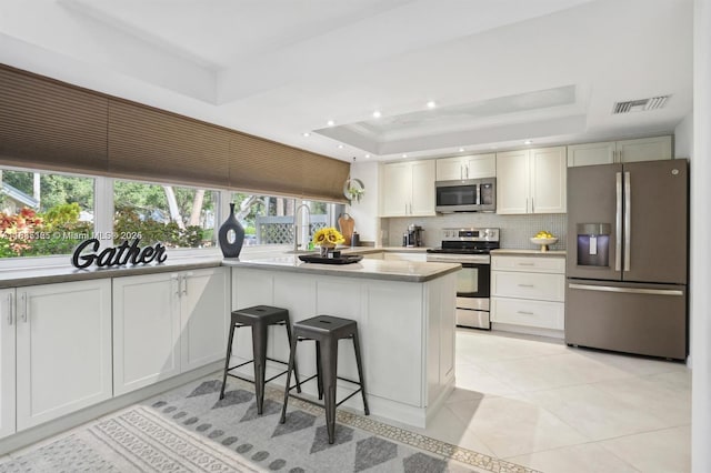 304 Andover Ct, Boynton Beach, FL 33436 - kitchen with stainless steel appliances, a tray ceiling, tasteful backsplash, light tile patterned flooring, and light countertops