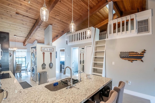 10391 Jasmine Ct, Pembroke Pines, FL 33026 - kitchen with estacked washer and dryer, wooden ceiling, light stone counters, hanging light fixtures, and a kitchen breakfast bar