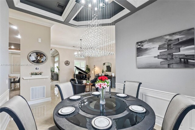 8346 SW 51st St, Davie, FL 33328 - tiled dining area featuring crown molding, a chandelier, arched walkways, a towering ceiling, and wainscoting