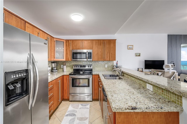 401 Ocean Dr Unit 1024, Miami Beach, FL 33139 - kitchen with appliances with stainless steel finishes, brown cabinetry, a peninsula, tasteful backsplash, and light stone counters