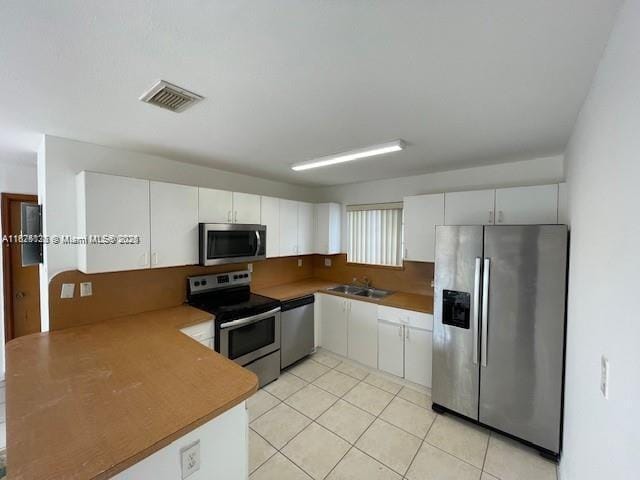 13723 SW 160th Ter, Miami, FL 33177 - kitchen featuring appliances with stainless steel finishes, a peninsula, white cabinetry, and light tile patterned flooring