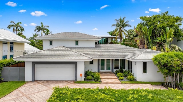 1231 96th St, Bay Harbor Islands, FL 33154 - view of front of home with an attached garage, french doors, stucco siding, and decorative driveway