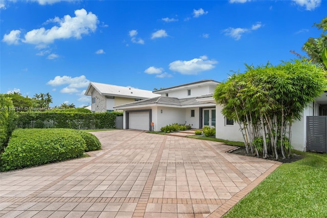 1231 96th St, Bay Harbor Islands, FL 33154 - view of front of house featuring an attached garage, decorative driveway, stucco siding, and french doors