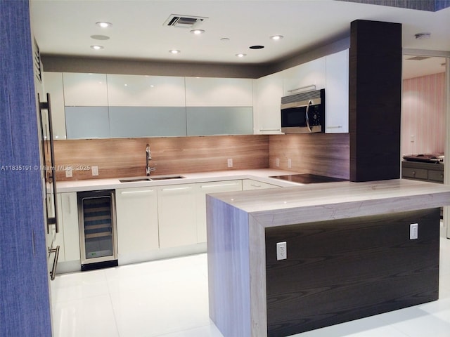17121 Collins Ave Unit 2803, Sunny Isles Beach, FL 33160 - kitchen featuring stainless steel microwave, wine cooler, modern cabinets, white cabinets, and light countertops