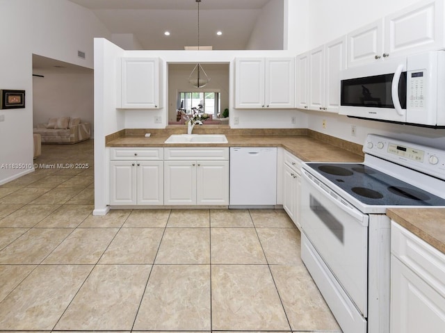 5570 Royal Lake Cir, Boynton Beach, FL 33437 - kitchen with white appliances, vaulted ceiling, white cabinets, light tile patterned floors, and recessed lighting