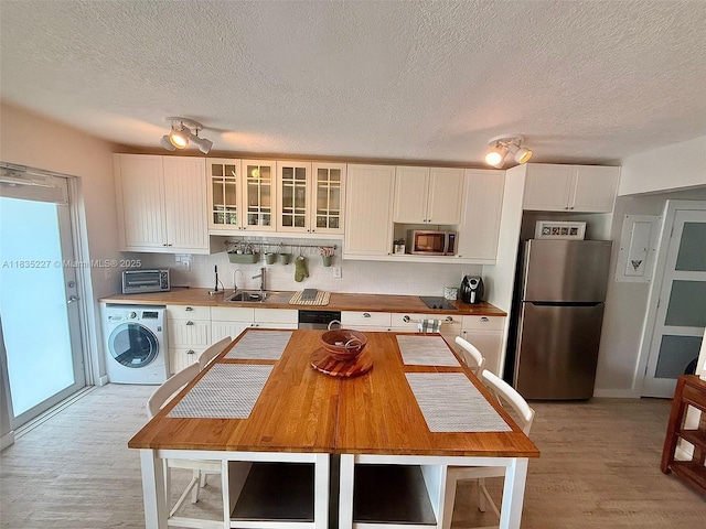 224 Meridian Ave Unit 10, Miami Beach, FL 33139 - kitchen with appliances with stainless steel finishes, washer / clothes dryer, light wood-style floors, white cabinets, and glass insert cabinets