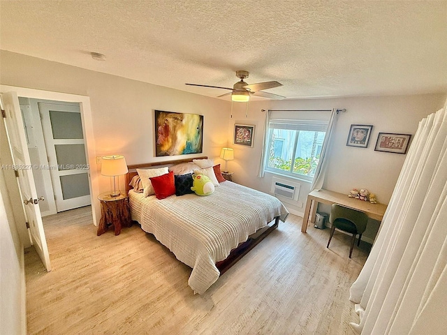 224 Meridian Ave Unit 10, Miami Beach, FL 33139 - bedroom with light wood-style flooring, a wall unit AC, a textured ceiling, and a ceiling fan