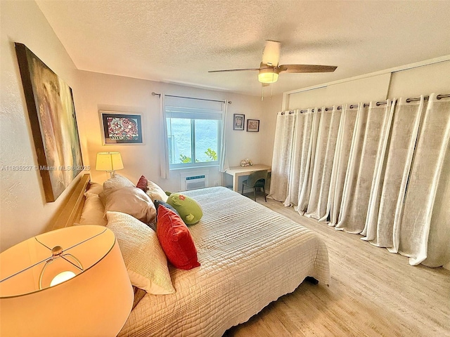224 Meridian Ave Unit 10, Miami Beach, FL 33139 - bedroom featuring wood finished floors, a wall mounted AC, a textured ceiling, and ceiling fan