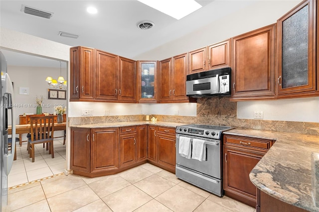 5001 SW 11th Cir, Margate, FL 33068 - kitchen with stainless steel appliances, a chandelier, light stone countertops, glass insert cabinets, and brown cabinetry