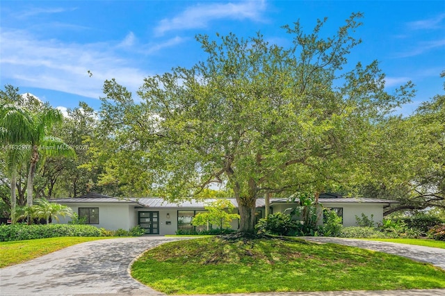 15121 SW 69th Ct, Palmetto Bay, FL 33158 - mid-century modern home featuring a standing seam roof, curved driveway, a metal roof, and stucco siding
