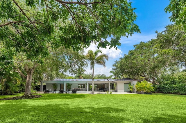 15121 SW 69th Ct, Palmetto Bay, FL 33158 - back of property with a lawn, stucco siding, a patio area, a metal roof, and a standing seam roof