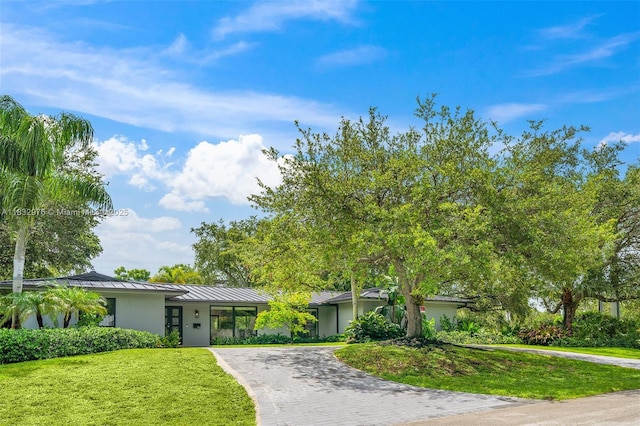 15121 SW 69th Ct, Palmetto Bay, FL 33158 - mid-century home with a standing seam roof, curved driveway, a front lawn, a metal roof, and stucco siding
