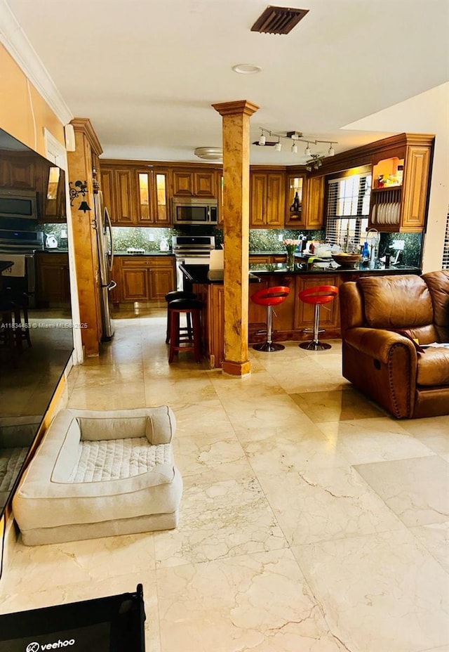 8565 NW 168th Ter, Miami Lakes, FL 33016 - kitchen with stainless steel appliances, a kitchen bar, open floor plan, tasteful backsplash, and brown cabinetry